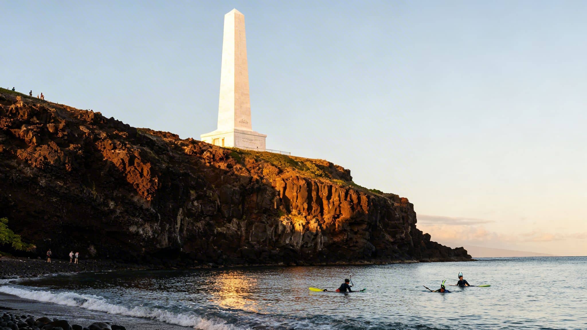 Snorkelers in Kealakekua Bay near Captain Cook Monument at sunset, Hawaii.