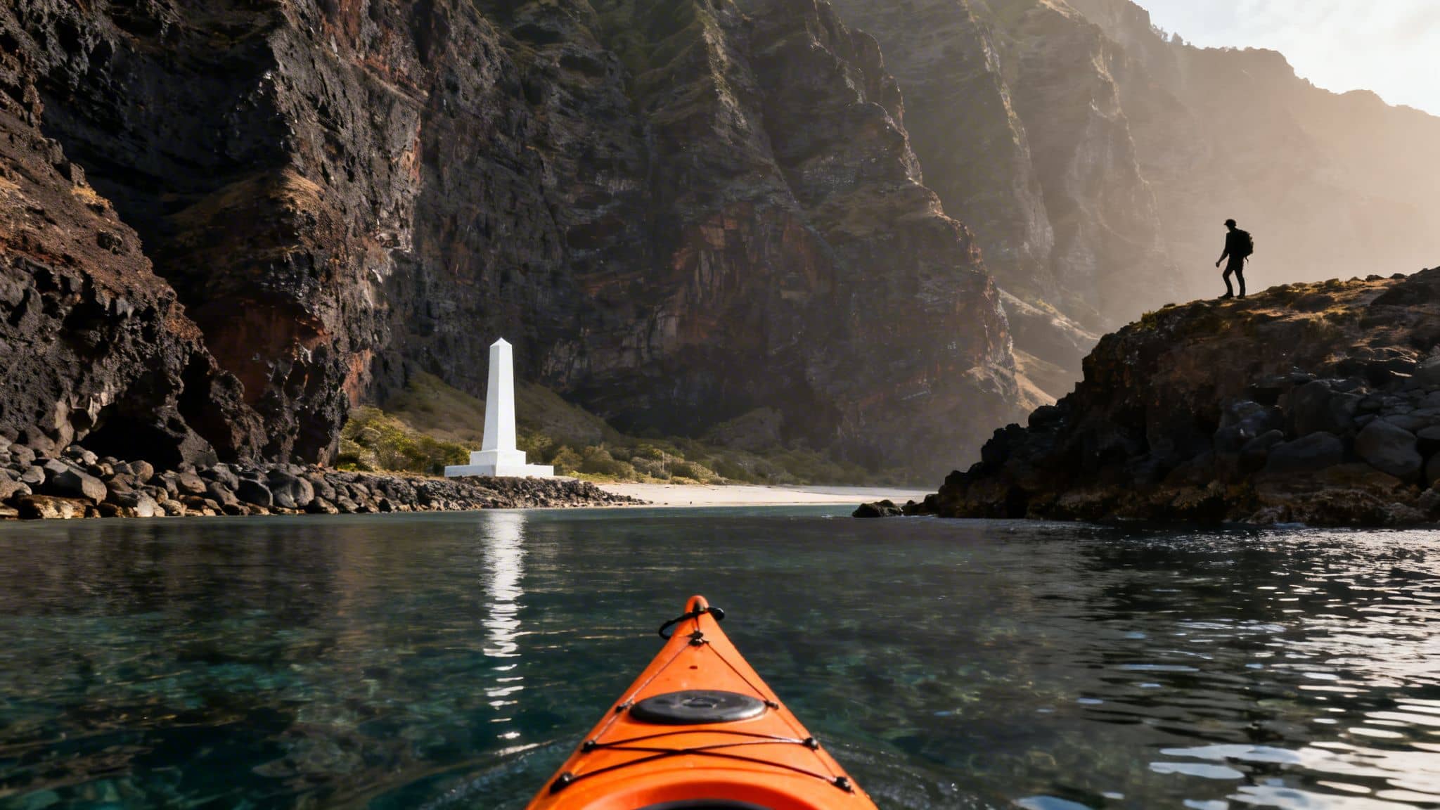 An orange kayak on clear water facing a white monument on a beach with towering cliffs and a hiker.