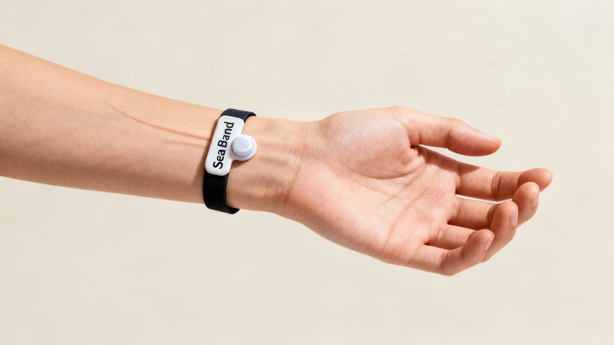 A close-up of a person's arm wearing a black Sea Band wristband for motion sickness.