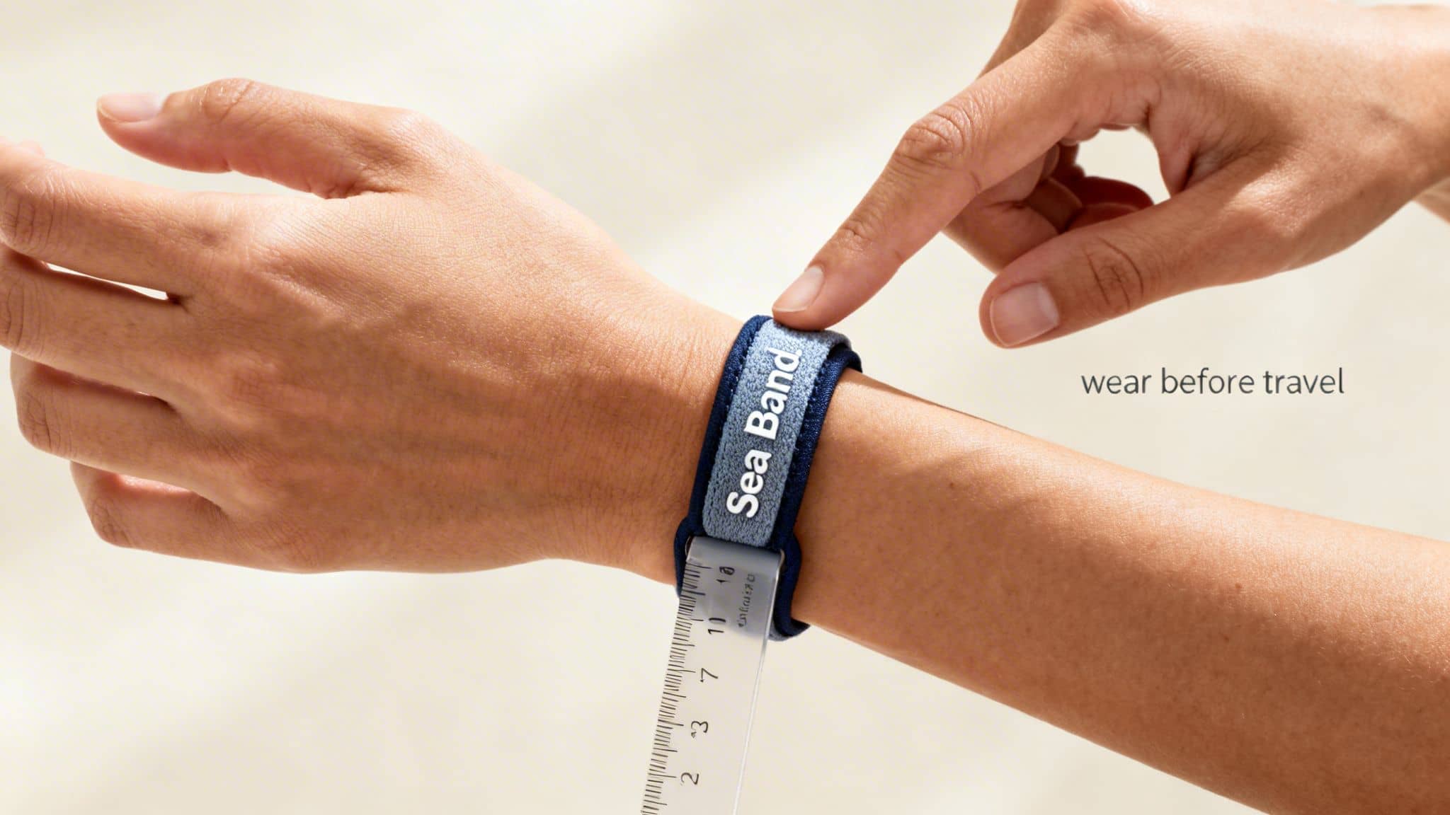 A person's arm wearing a blue 'Sea Band' bracelet on their wrist, with text 'wear before travel' visible.