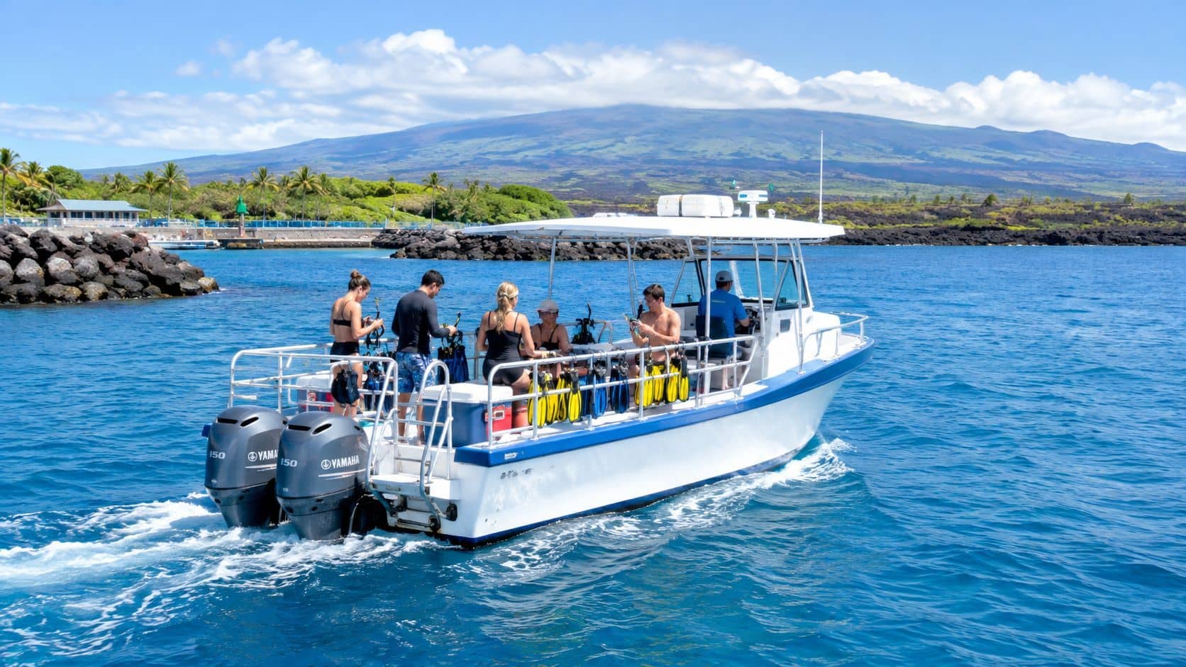A group of people prepare for snorkeling on a boat near the Hawaiian coast on a sunny day.