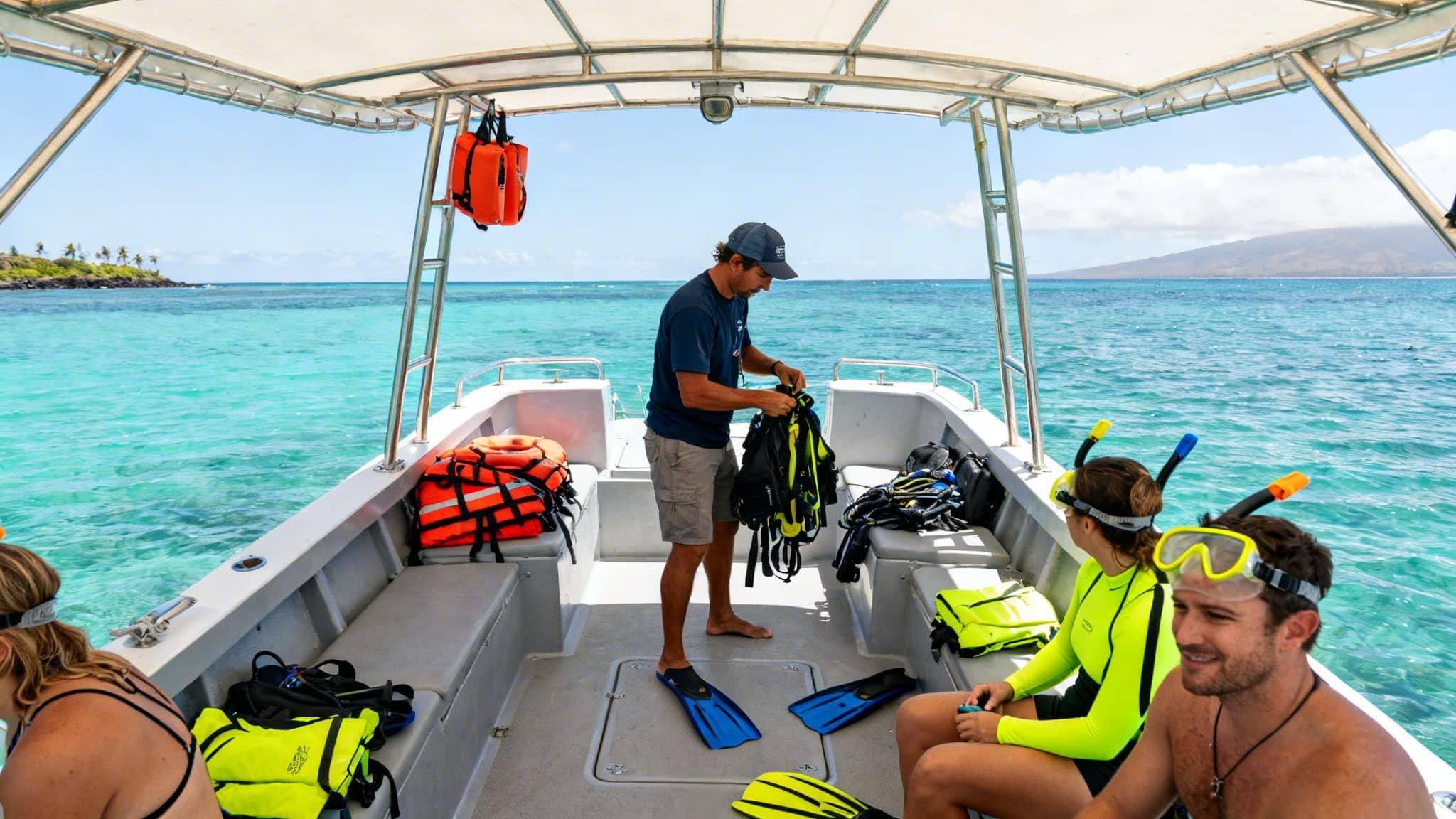 People on a boat preparing for snorkeling in clear turquoise water near a tropical island.