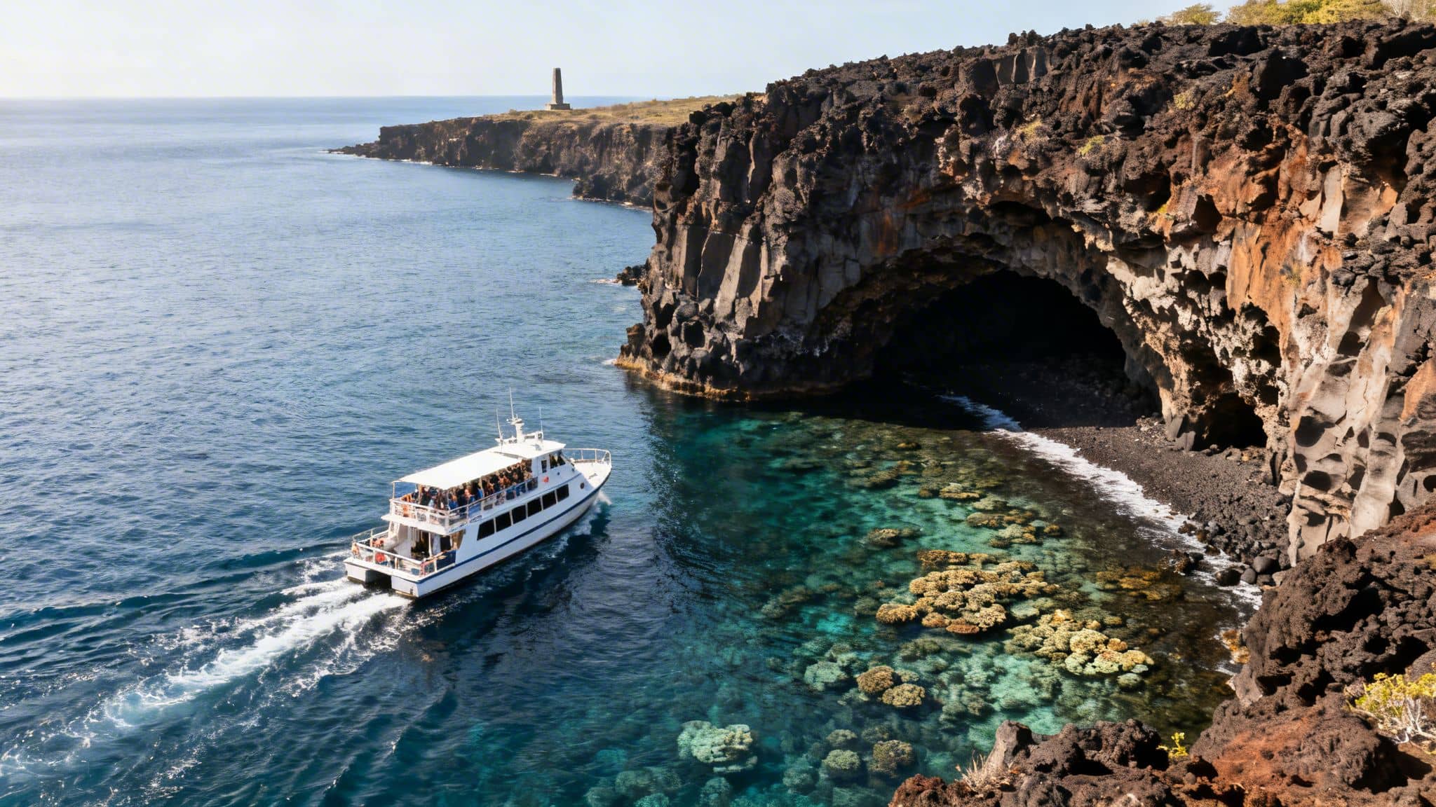 A tour boat passes stunning volcanic sea cliffs, a large cave, and vibrant coral reefs.