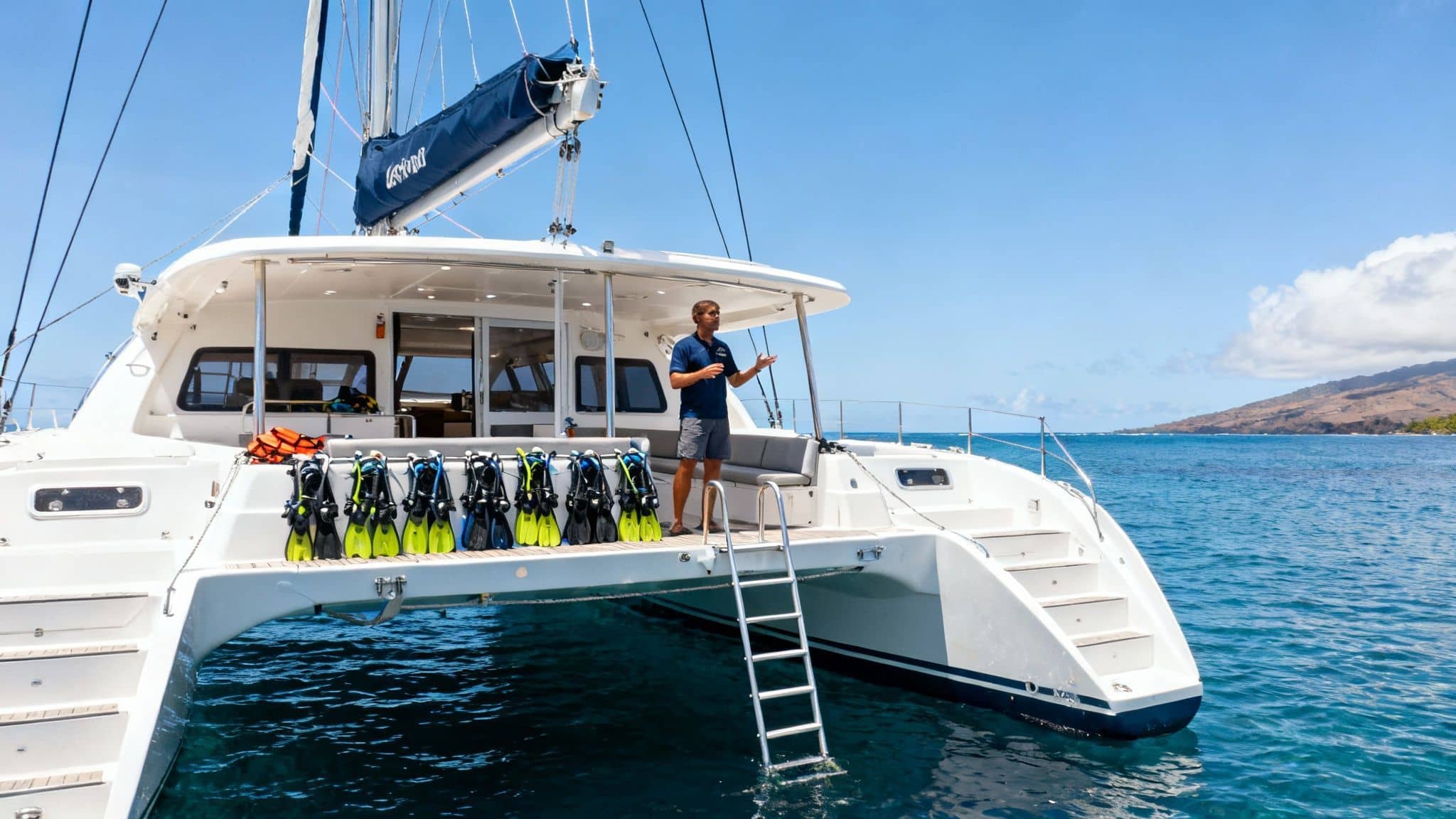 Luxury catamaran yacht with diving equipment and crew member preparing for snorkeling tour