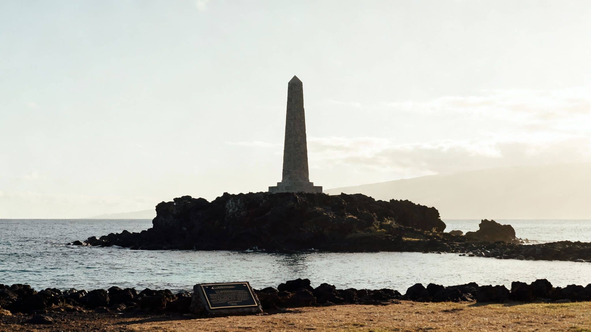 Historic obelisk monument on a volcanic rock island, commemorating Captain Cook's landing.