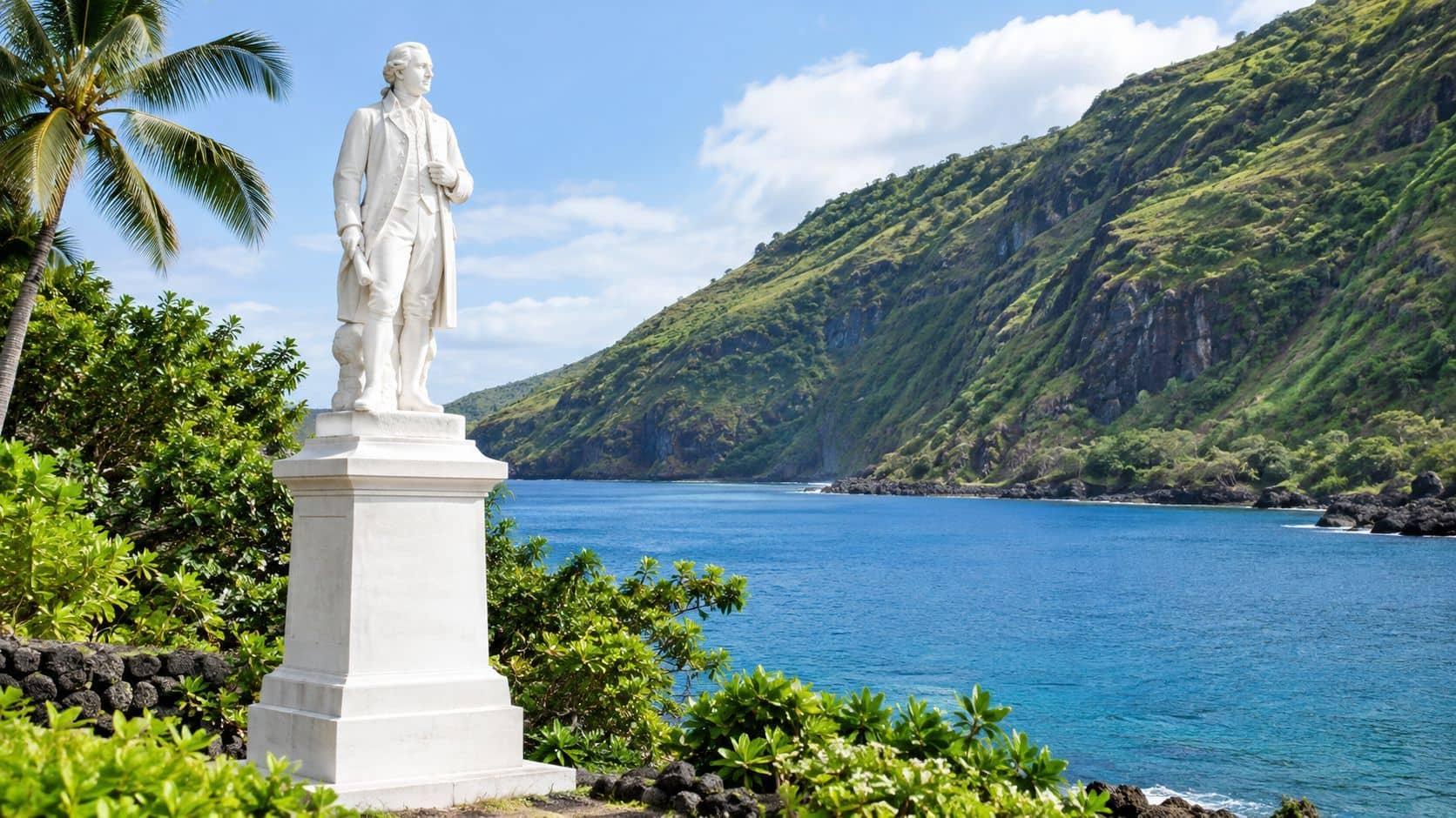 A white statue of Captain James Cook standing against a scenic tropical ocean bay and green mountains.